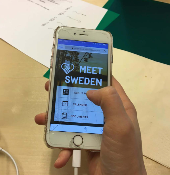 En hand som håller i en mobiltelefon som visar appen Meet Sweden.